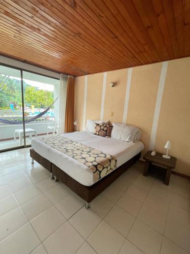 a bedroom with a bed and a large window at Hotel Hacienda El Diamante in Villeta