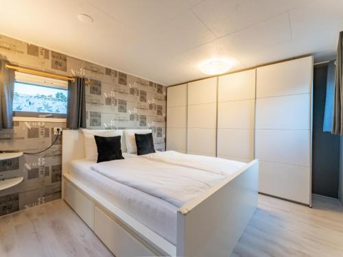a white bedroom with a large white bed and a sink at Vakantiehuis Vos in Hulshorst