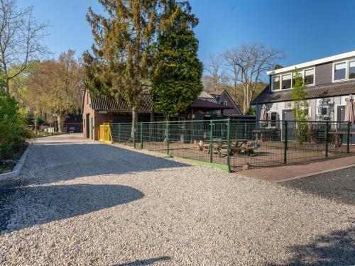 a gravel road with a fence in front of a building at Vakantiehuis Vos in Hulshorst
