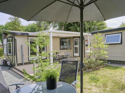 a caravan with a table and an umbrella at Vakantiehuis Vos in Hulshorst
