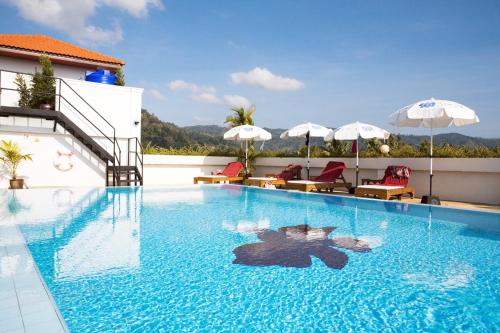 ein Swimmingpool mit Stühlen und Sonnenschirmen auf einem Gebäude in der Unterkunft Orchid Kathu Heights Service Apartments in Kathu