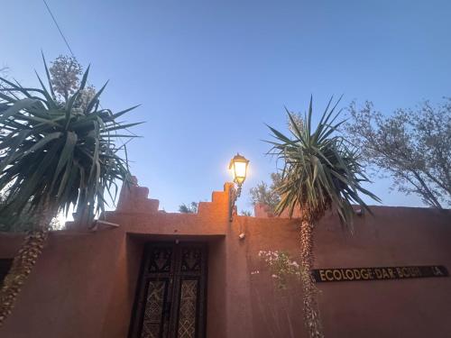 a street light on the side of a building with palm trees at Ecolodge Dar bouhouta in Tahannout