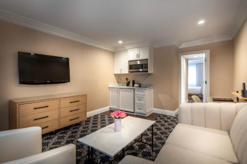 a living room with a couch and a tv at Beverly Hills Plaza Hotel & Spa in Los Angeles