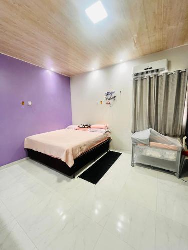 a bedroom with a bed and a purple wall at Casa cidade nova in Ananindeua