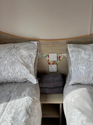 a bedroom with two beds and a wooden headboard at Relax&Dreams caravan in Port Seton