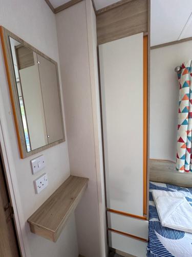 a small bathroom with a mirror and a bed at Relax&Dreams caravan in Port Seton