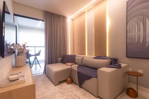 un soggiorno con un divano e un tavolo di Apartamento 2 suítes, Charme mediterrâneo, com Piscina e Academia a Itapema
