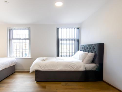 a bedroom with a bed and two windows at Best 2BR Flat in Cardiff Near Town Centre in Cardiff