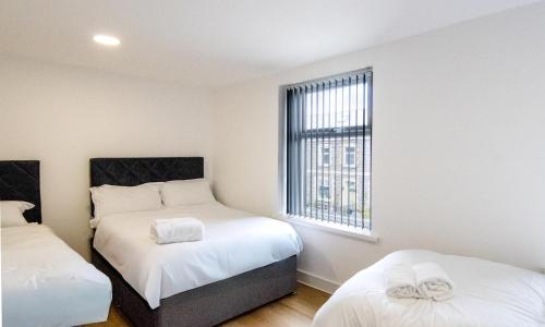 a small bedroom with two beds and a window at Best 2BR Flat in Cardiff Near Town Centre in Cardiff