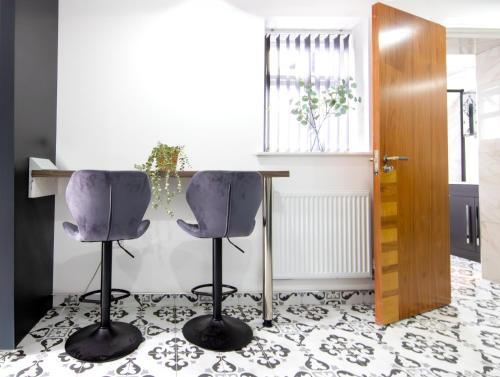 a kitchen with two bar stools and a table at Best 2BR Flat in Cardiff Near Town Centre in Cardiff