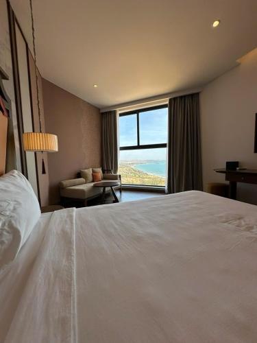 a bedroom with a large bed with a view of the ocean at The Raclay Mandala Cham Bay Mui Ne - Phan Thiet in Phan Thiet