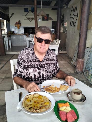 un uomo seduto a un tavolo con un piatto di cibo di Bali Villa coral ad Amed