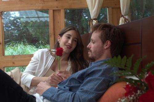 a man and woman sitting on a couch holding a rose at Casa Mujer Villa Agueda in Chocontá