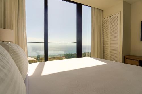 a bedroom with a white bed and a large window at Penthouse At Arihini West Bay in Coxen Hole