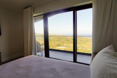 a bedroom with a bed and a large window at Penthouse At Arihini West Bay in Coxen Hole
