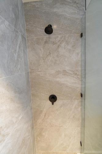 a shower with a glass door with a tile floor at Penthouse At Arihini West Bay in Coxen Hole