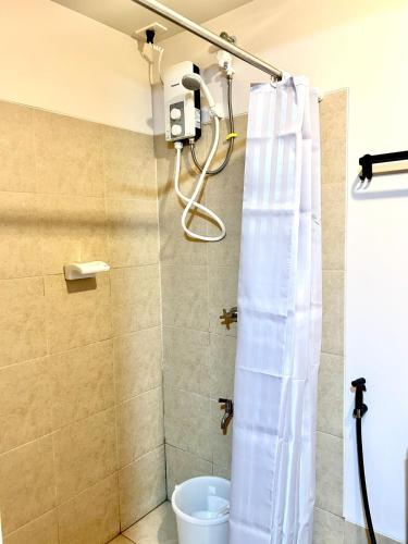 a shower with a white shower curtain in a bathroom at Cozy Studio near Nuvali, Enchanted Kingdom - Private Cinema with Netflix & Disney Plus with Free Pool Access in Silang