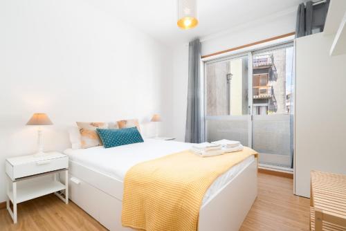 a white bedroom with a bed and a window at Renovated 3BR Apt Near City Hotspots with Great Value in Porto