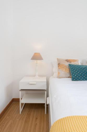 a bed with a nightstand next to a bed with a lamp at Renovated 3BR Apt Near City Hotspots with Great Value in Porto