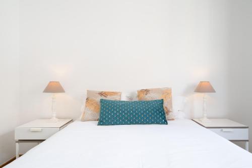 a white bed with blue pillows and two lamps at Renovated 3BR Apt Near City Hotspots with Great Value in Porto