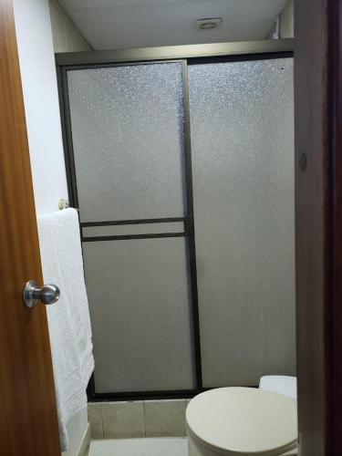 a bathroom with a glass shower door with a toilet at Departamento con piscina 8 in Salinas