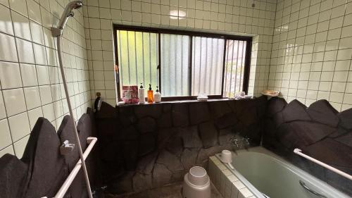 a bathroom with a bath tub and a window at 民泊みどりやね in Ibusuki