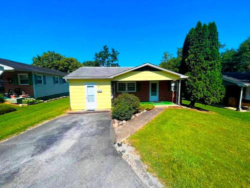 a yellow house with a driveway in a yard at Centralized Modern Home in Johnson City in Johnson City