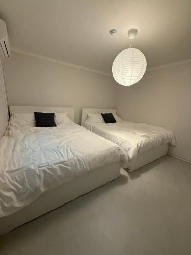 two beds in a white bedroom with a chandelier at Staymuk Seochon, Center of Seoul in Seoul