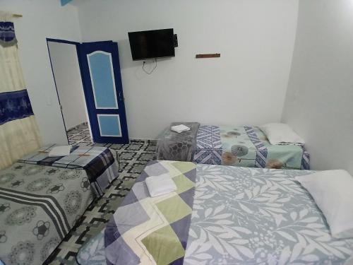a room with two beds and a tv on the wall at Vista Farallones Hostel in Jardin