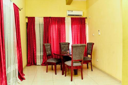 a dining room with red curtains and a table and chairs at Hopeland Apartments Limbe in Limbe