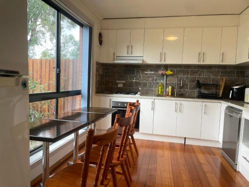 a kitchen with white cabinets and a table and chairs at Home in Laverton 19 Minutes to Melbourne CBD in Laverton