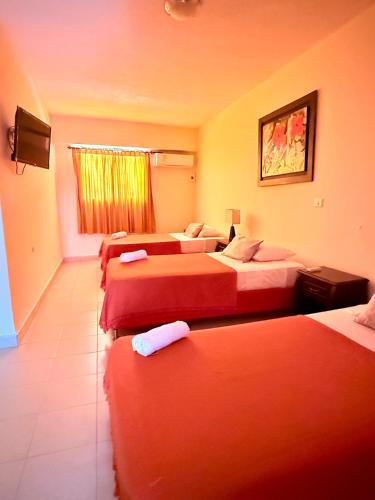 a hotel room with three beds and a window at Hotel Sorrento 72 in Barranquilla