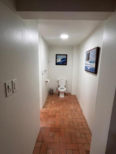 a bathroom with a toilet and paintings on the wall at Surfers bungalow 5 min walk to the beach in Tamarindo