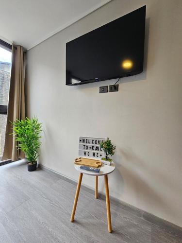 a room with a table with a tv on the wall at Alojamiento a pasos de Movistar Arenas, Parque O Higgins, Universidad de Chile y Ministerio de Justicia in Santiago