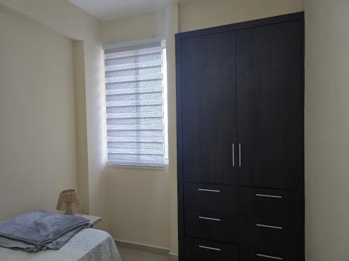 a bedroom with a large black cabinet and a bed at Acogedor y Centrico Apto 2hab-1baño in Maracaibo