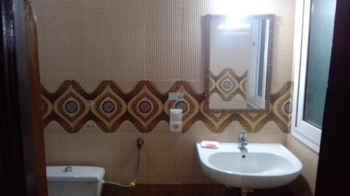 a bathroom with a sink and a toilet and a mirror at La Belle Apartement 2x2 - Grand Mbao, plage in Dakar