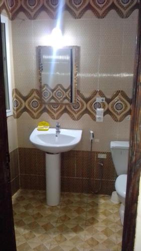 a bathroom with a sink and a toilet and a light at La Belle Apartement 2x2 - Grand Mbao, plage in Dakar
