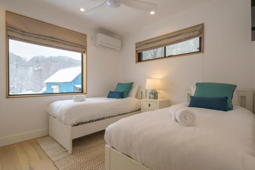 two beds in a room with a window at Kogane Hills Niseko in Rankoshi