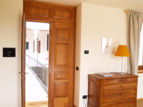 a room with a wooden door and a dresser with a lamp at Casa Botta - Luino Lago Maggiore in Luino