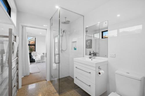 a white bathroom with a sink and a shower at Lakeside Retreat - Cromwell Holiday Home in Cromwell