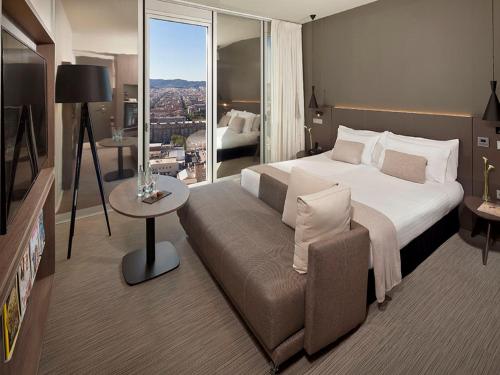 um quarto de hotel com uma cama e um sofá em The Level at Melia Barcelona Sky em Barcelona