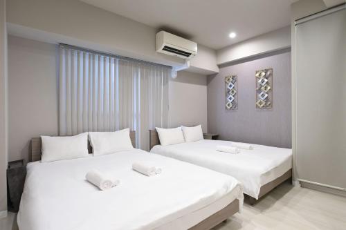 two beds in a hotel room with white sheets at Ostay Kitahama Hotel Apartment in Osaka