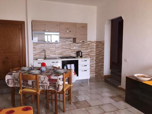 eine Küche mit einem Tisch und Stühlen sowie eine Küche mit einem Herd in der Unterkunft Appartamenti Abbaidda 2 in Valledoria