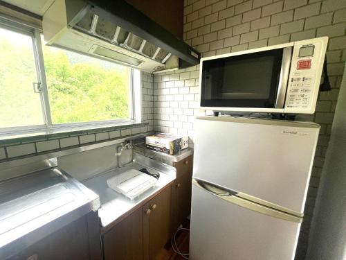 a kitchen with a refrigerator and a microwave at オーシャン日南らくだの宿 in Nichinan