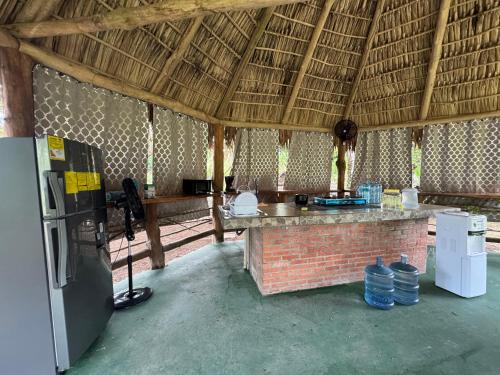 a kitchen in a straw hut with a refrigerator at Casa Nova at La Escapadita in Esterillos