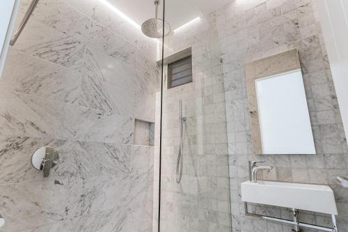 un bagno con doccia, lavandino e specchio di Ultimate Beachfront Living Sunshine Beach a Sunshine Beach
