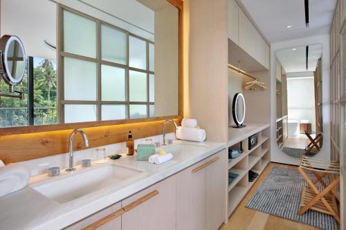 a bathroom with a sink and a large mirror at Bumi Kinar Skylight in Ubud