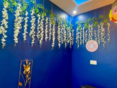a blue wall with white flowers hanging from it at Villa De Dunes 369, Orchid Home in Bengaluru