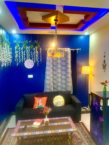 a living room with a couch and a blue wall at Villa De Dunes 369, Orchid Home in Bengaluru