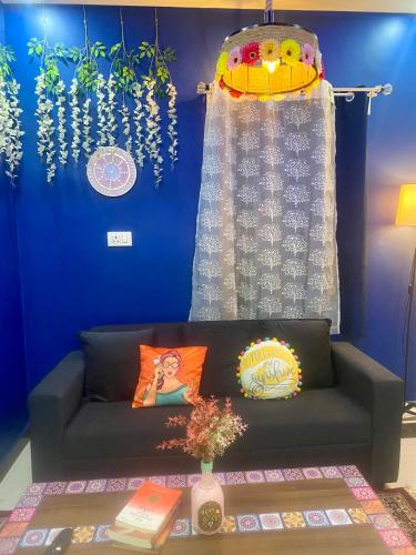 a living room with a couch and a blue wall at Villa De Dunes 369, Orchid Home in Bengaluru